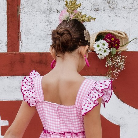 Vista trasera de bata rociera niña con cierre de cremallera y tirantes decorados.