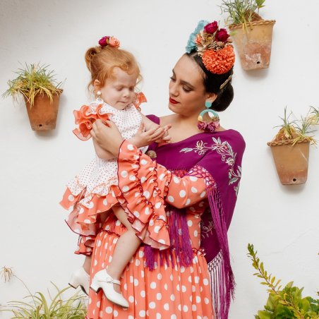 Vestido canastero coral con mantoncillo flamenco a tono, bordado y flecado a mano.